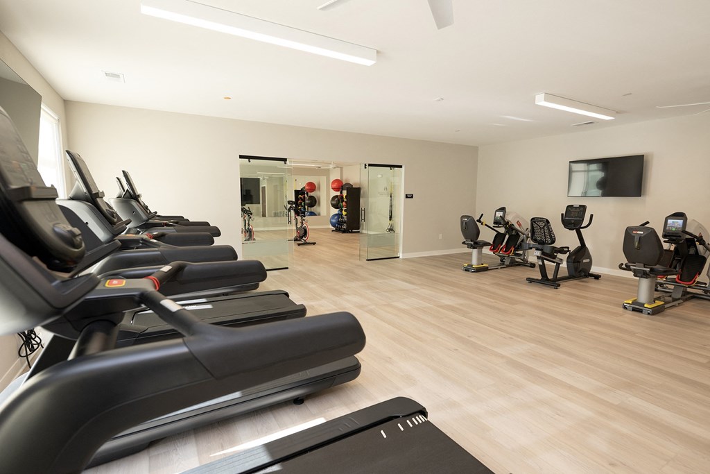 a gym filled with cardio machines and a tv
