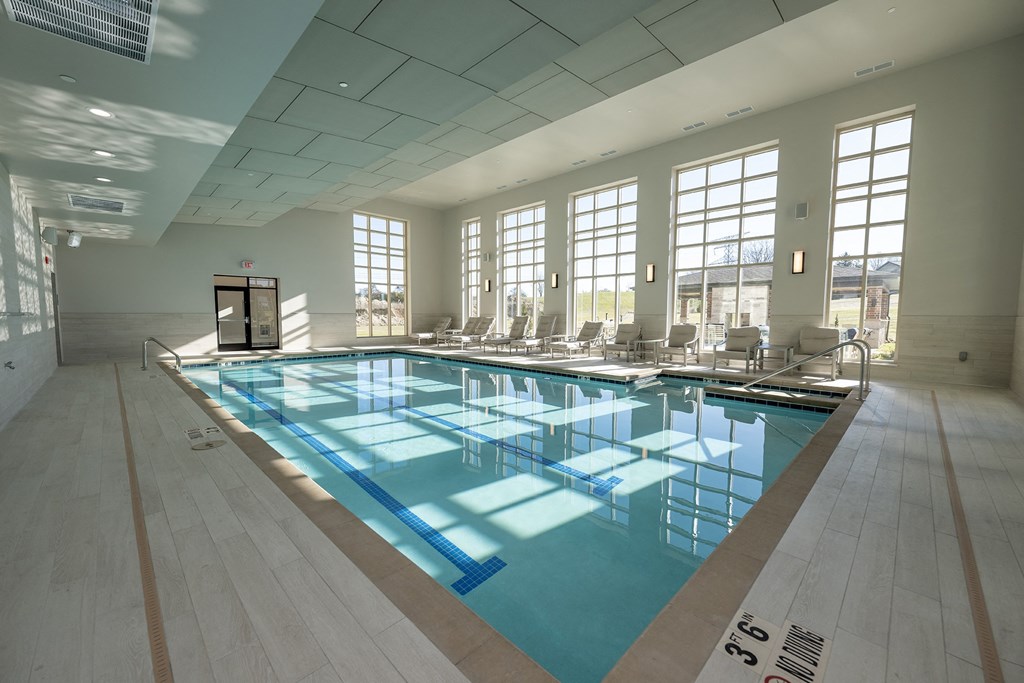 a large swimming pool with chairs in a building with large windows