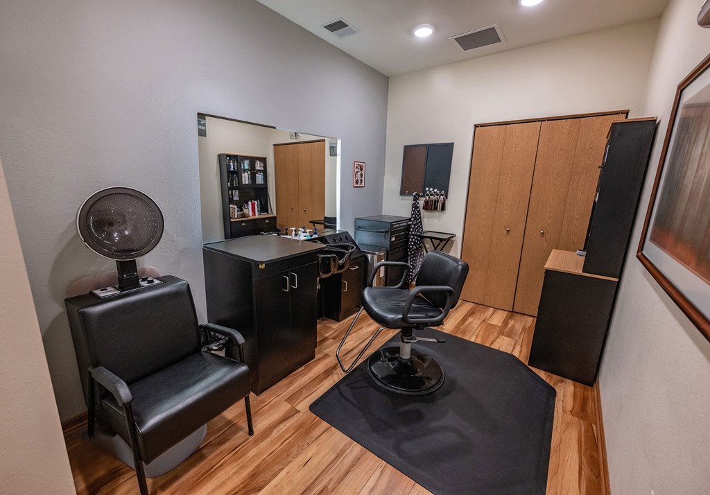 A room with a black chair and a black table with a fan on it.