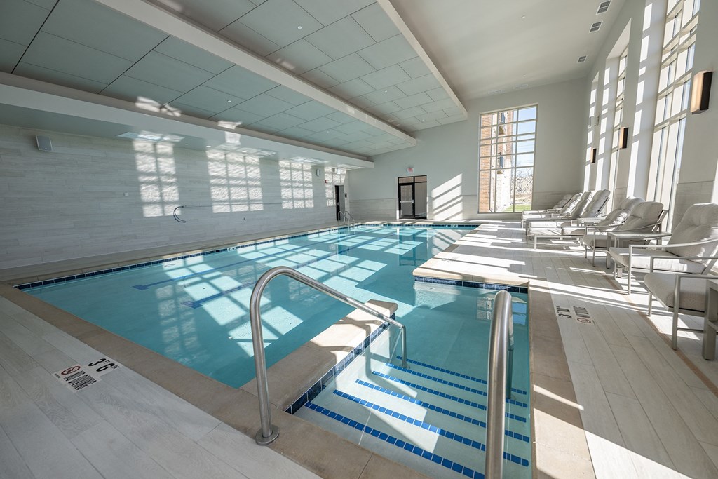 a swimming pool with chairs in a building with large windows