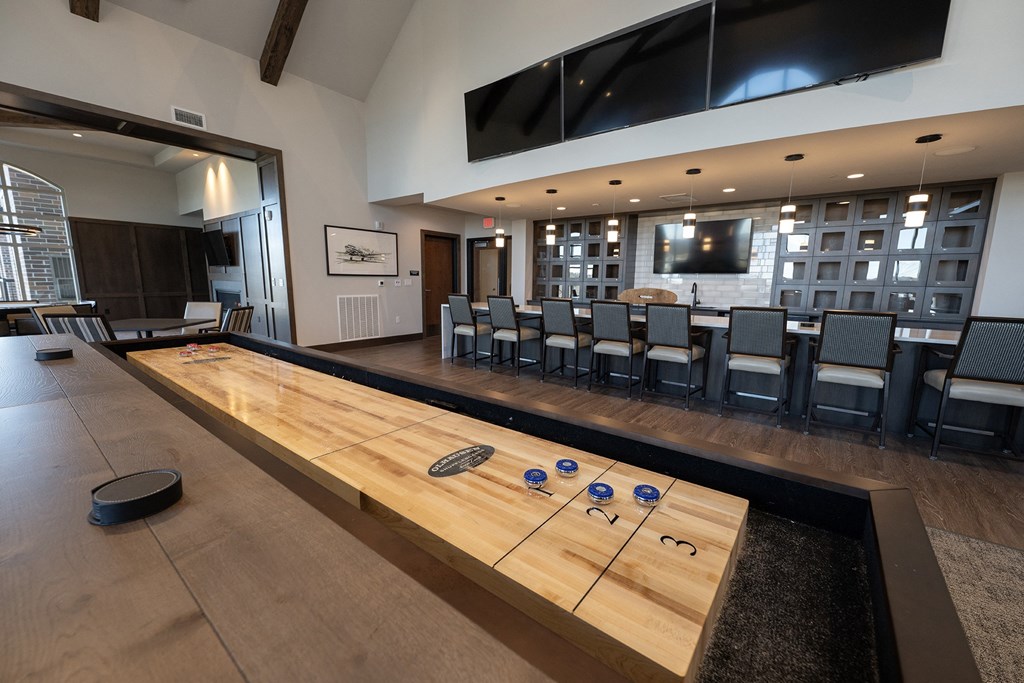 a shuffleboard table in the center of a large room with chairs and a television