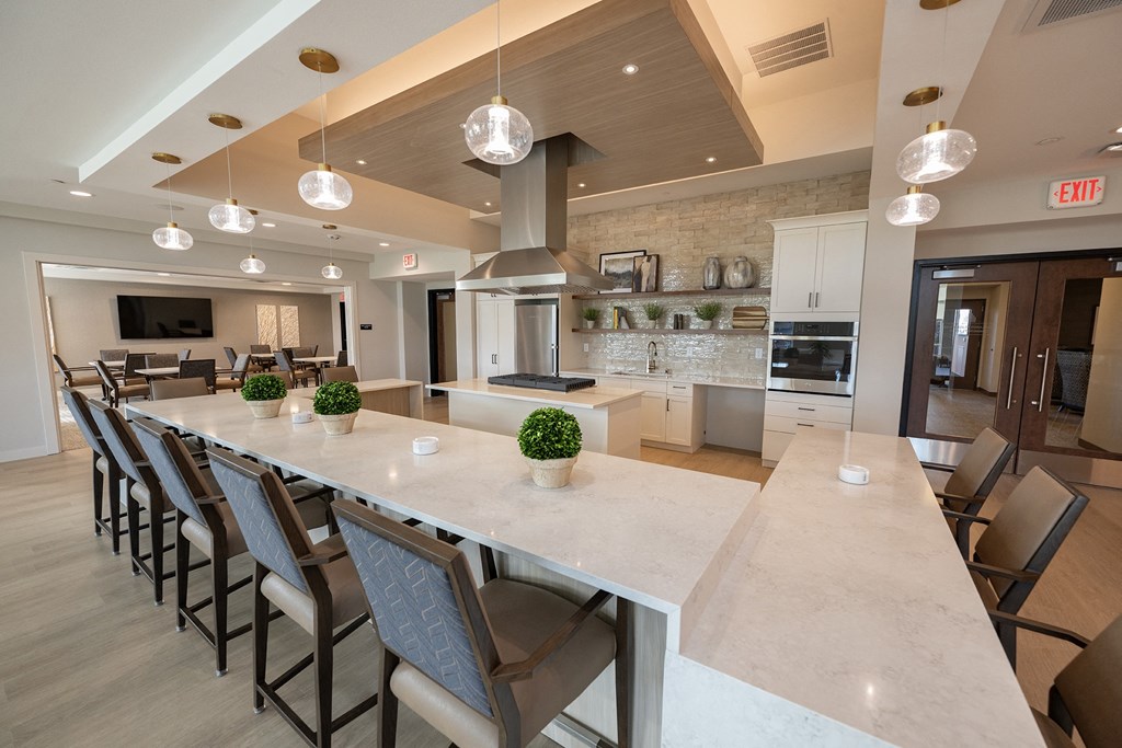 a large kitchen with a long counter and chairs in front of a table