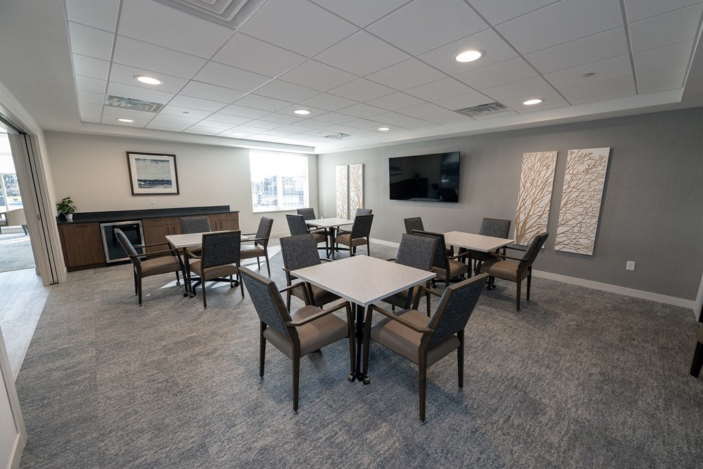 a community room with tables and chairs and a television