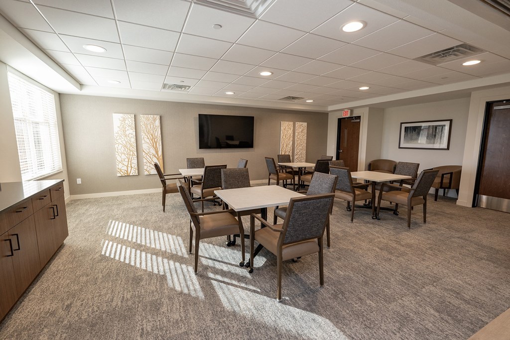 a community room with tables and chairs and a television