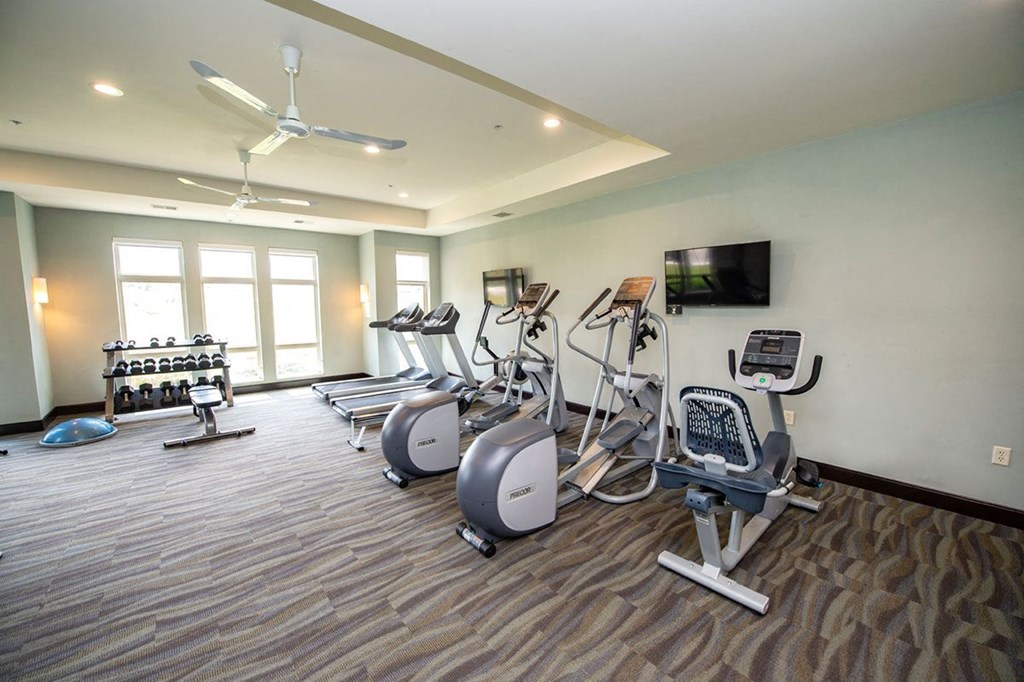 a gym with cardio machines and a tv