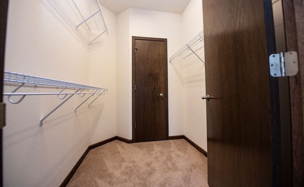 a walk in closet with a wooden door and a hanging rack