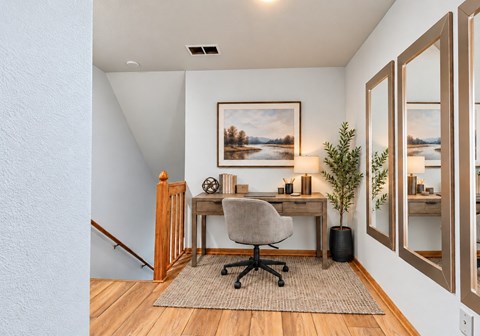 A room with a desk, chair, and a painting on the wall.