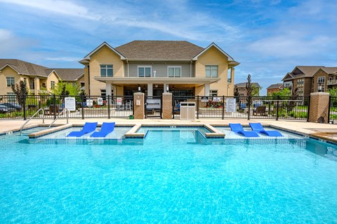 a large swimming pool with blue chairs in front of a house