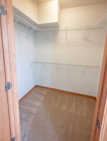 an empty closet in a home with white walls and carpet
