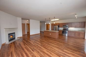 an empty living room with a fireplace and a kitchen