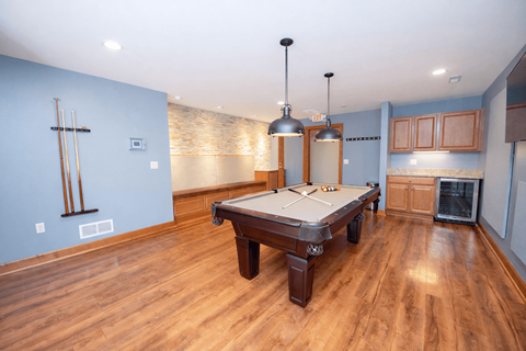 A pool table in a room with wooden floors and a light blue wall.