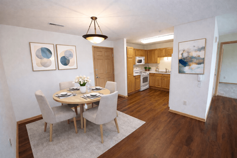 A dining room with a table set for two and a kitchen in the background.
