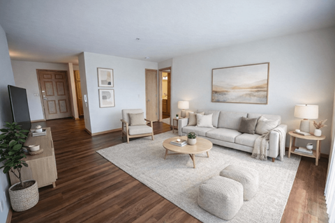 A living room with a white couch, a wooden coffee table, and a painting on the wall.