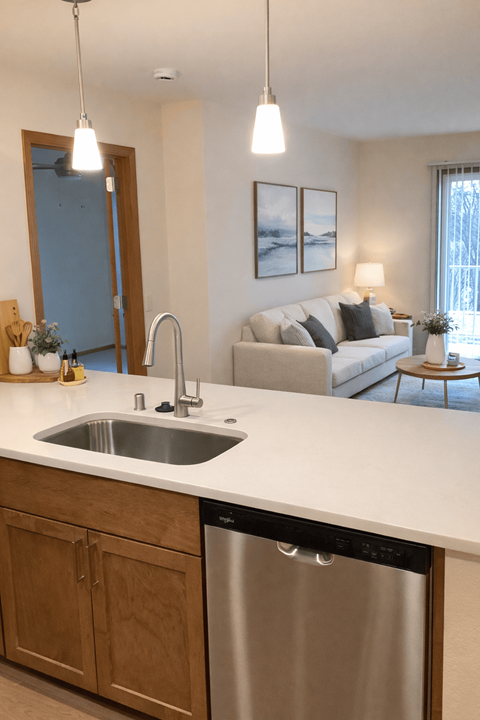 A modern kitchen with a stainless steel dishwasher and a white countertop.