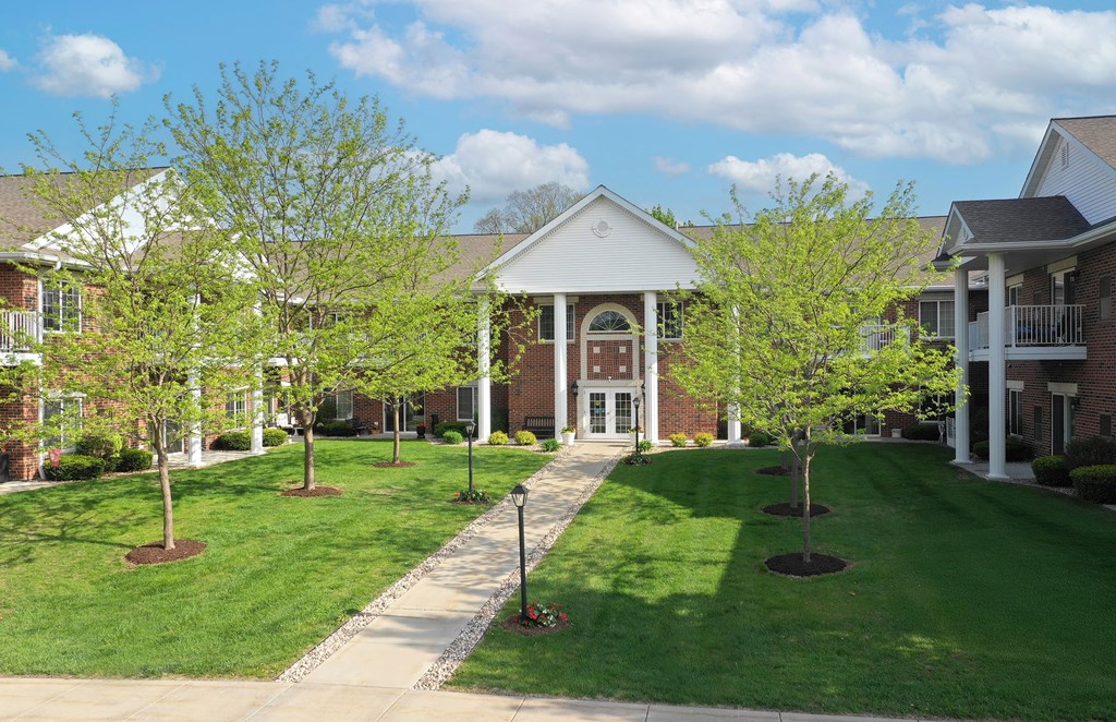 A building with a white roof and a red door is surrounded by green trees.