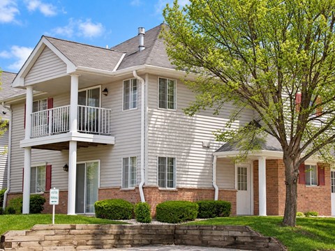 A two-story house with a balcony and a tree in front.