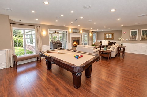 A pool table in the middle of a room with a fireplace and couches.