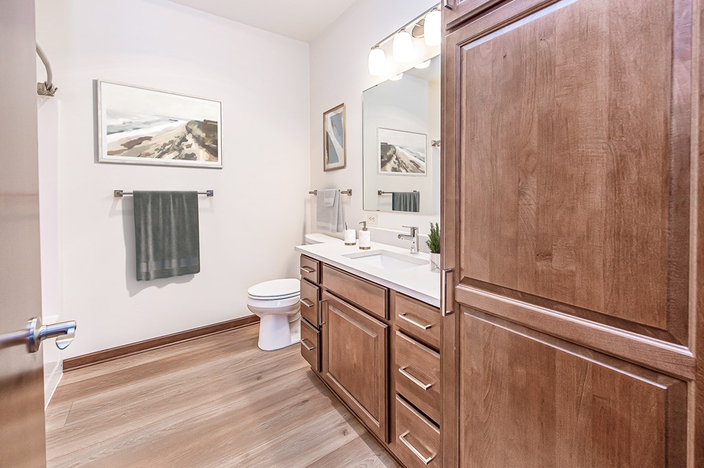a bathroom with white walls and wood flooring