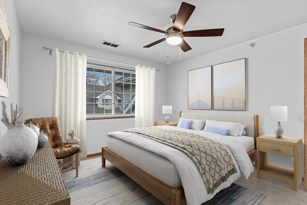 A bedroom with a large bed, a chair, and a table with a vase on it.