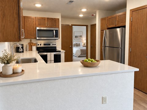 A kitchen with a white countertop and wooden cabinets.
