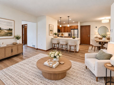 A living room with a coffee table in the center and a dining area in the background.