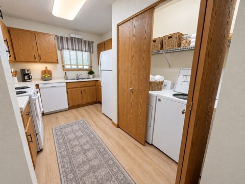 A kitchen with white appliances and wooden cabinets.