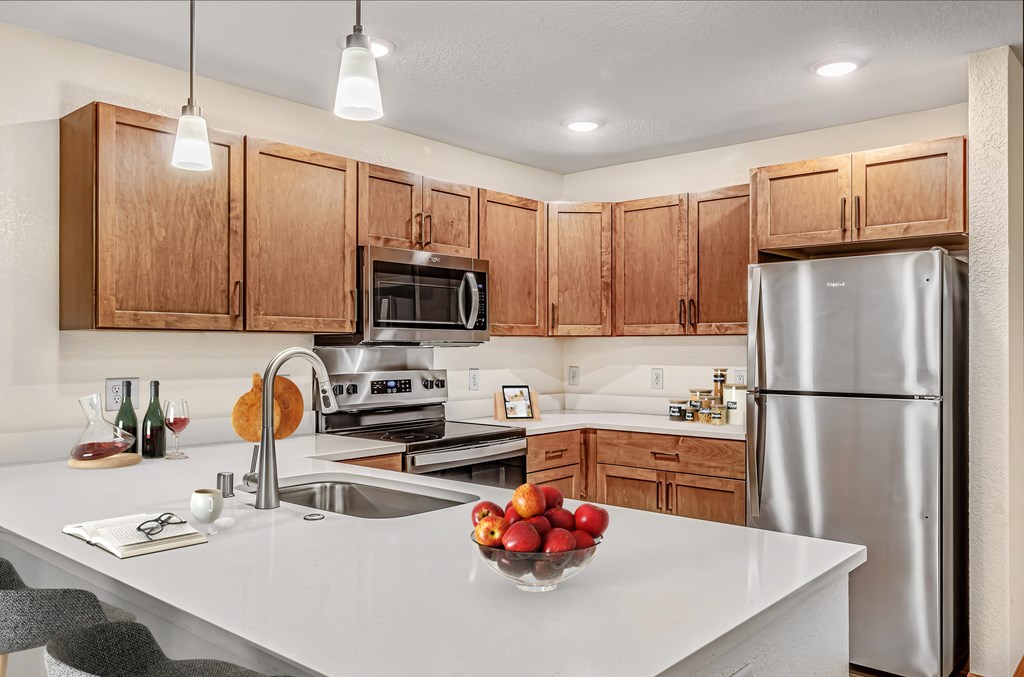 A kitchen with a white counter top and wooden cabinets.