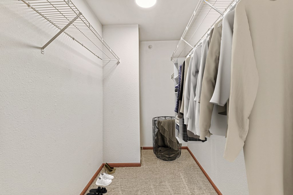 A hallway with clothes hanging on a rack and a pair of shoes on the floor.