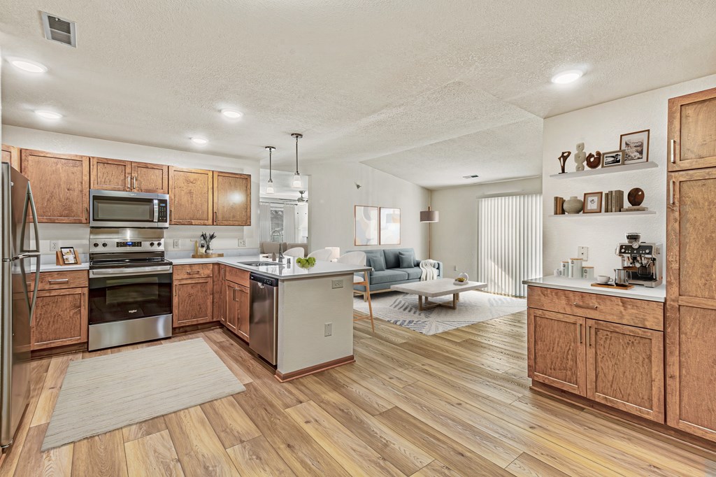 A kitchen with wooden floors and a refrigerator on the left.