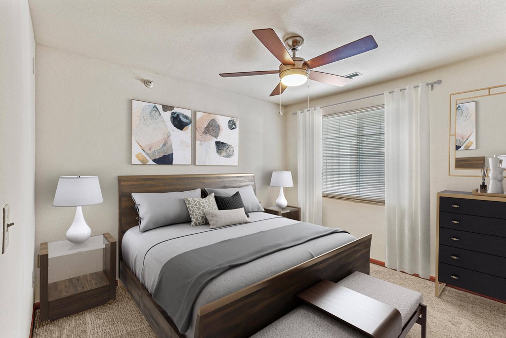 A bedroom with a bed, nightstand, and a ceiling fan.