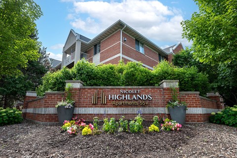 The image shows a brick building with a sign that reads "Nicolet Highlands Apartments 55+".