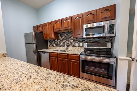A kitchen with brown cabinets and a granite countertop.