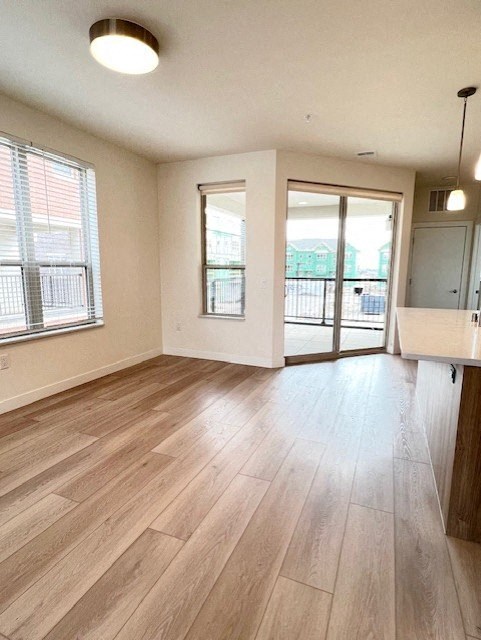 an empty living room with wood flooring and a door to a balcony