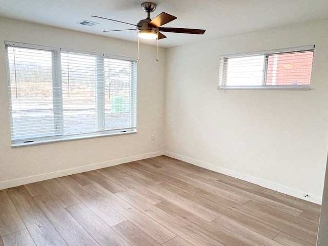 an empty living room with a ceiling fan and two windows