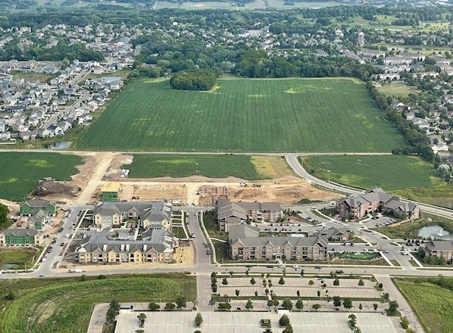 an aerial view of a neighborhood with a field in the background