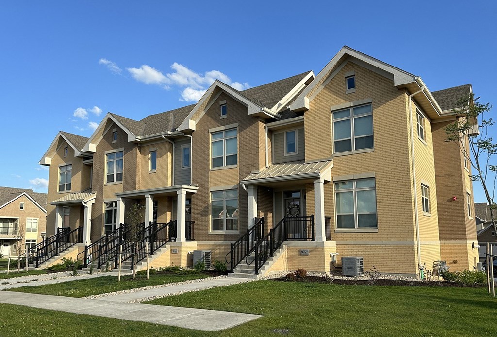 a row of brick homes with stairs and grass in front