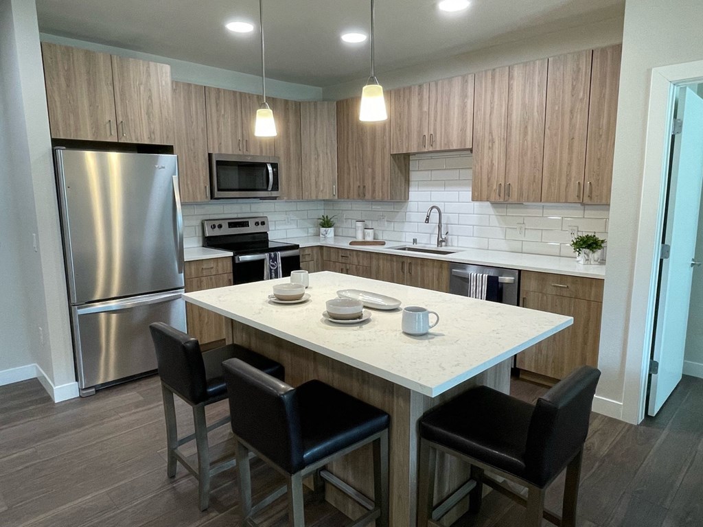 a kitchen with a large island and a stainless steel refrigerator