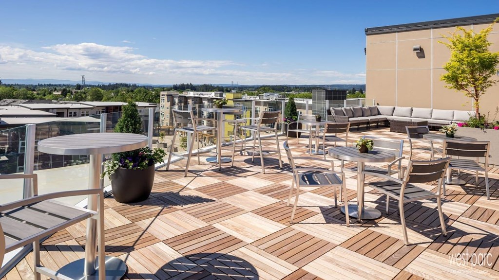 A rooftop patio with tables and chairs at west parc apartments near portland and beaverton.