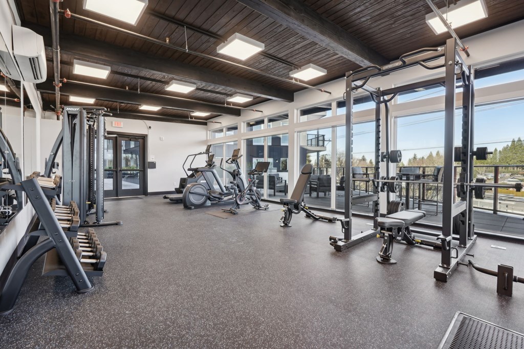 A spacious gym with a variety of equipment including treadmills, weights, and exercise machines wood market hall view at AVIVA Apartments in Gresham Oregon