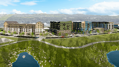 A modern building complex is surrounded by a grassy area and a body of water.