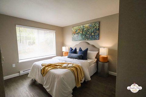 A bedroom with a white bed and a painting on the wall.