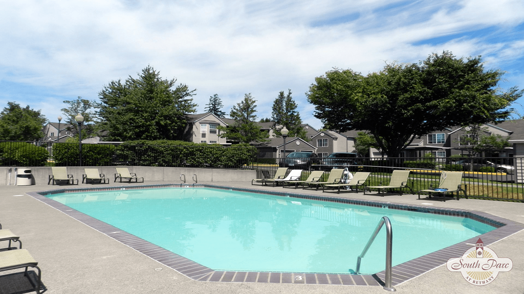 a swimming pool with chairs and trees in front of a house