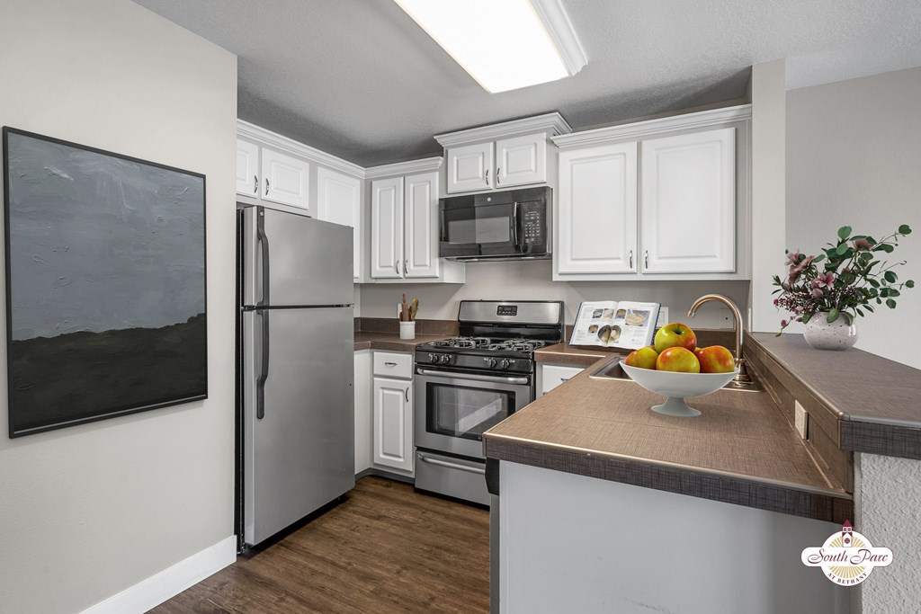 A kitchen with a refrigerator, oven, and microwave.