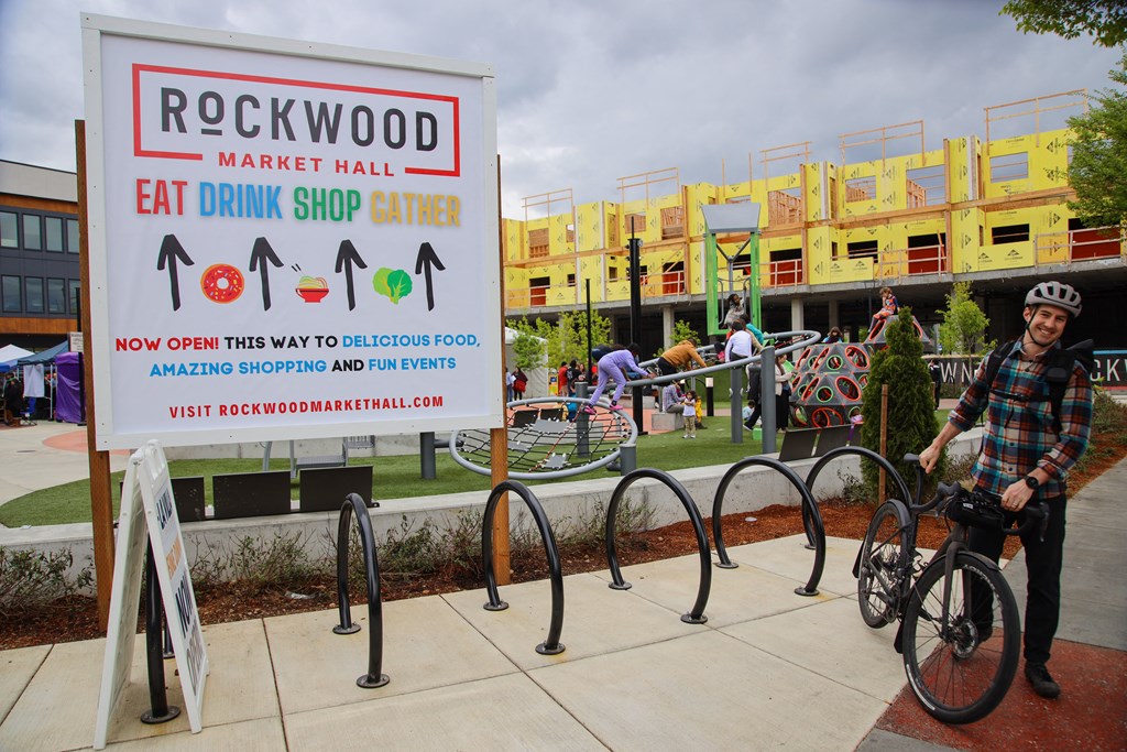 a man on a bike in front of a rockwood market hall sign