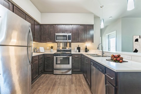 A modern kitchen with dark wood cabinets and stainless steel appliances.