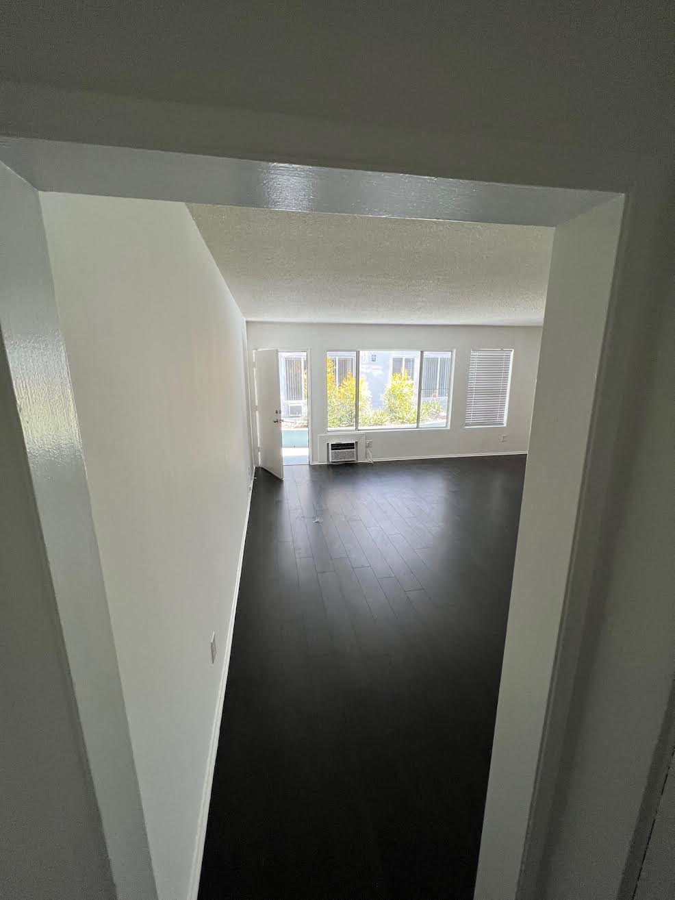 Living room with hardwood floor looking towards front door in apartment unit at The Carlton in Hollywood, California.