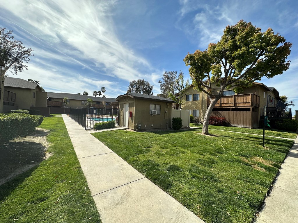 Buildings and landscaping around gated swimming pool at Riverdale Apartment Homes in Hemet, California.