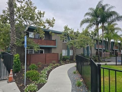 A building with a black fence and a sidewalk in front of it.
