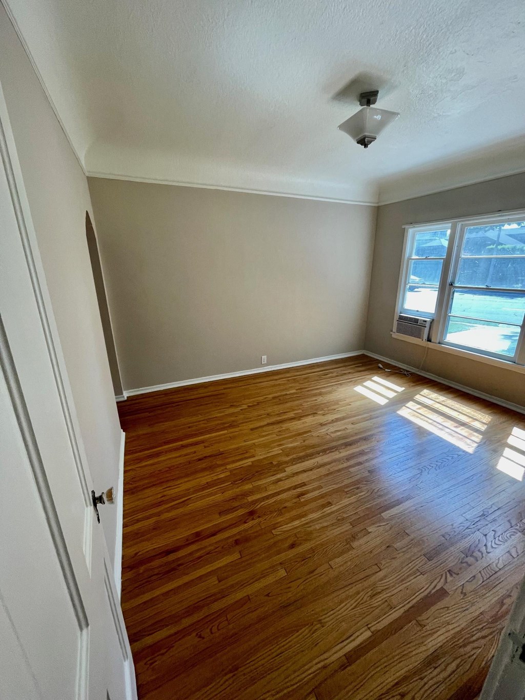 Bedroom with hardwood floors and big windows at Orange Grove Apartments in Pasadena, CA.