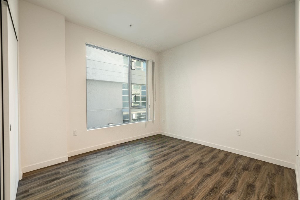 an empty living room with a large window and wood flooring